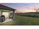 A covered patio extends to a view of a green space, trees, and sunset sky at 5226 Mahogany Dr, Mount Dora, FL 32757