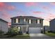Two-story home featuring a two-car garage, covered porch, and landscaped front yard at sunset at 5226 Mahogany Dr, Mount Dora, FL 32757