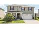 Two-story home with a well-manicured lawn, two-car garage, and a charming front porch at 5226 Mahogany Dr, Mount Dora, FL 32757
