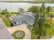 Waterfront home featuring well-manicured lawn, long driveway, mature trees, and vibrant blue front door at 716 Palm Circle Dr, Port Orange, FL 32127