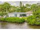 The house has a backyard patio, white fence, and lush, mature landscaping next to the water at 716 Palm Circle Dr, Port Orange, FL 32127