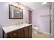 Well-lit bathroom featuring a wooden vanity with a marble countertop, a toilet, and neutral-colored walls at 7730 Pineapple Dr, Orlando, FL 32835
