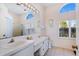 Bright bathroom featuring double sinks, a large mirror and arched windows at 12137 Dickenson Ln, Orlando, FL 32821