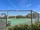 View of tennis courts through the fence and trees, set in a well-maintained community at 12137 Dickenson Ln, Orlando, FL 32821