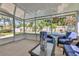 Enclosed patio featuring blue chairs, a glass-top table, and a view of the backyard and pool at 1525 Orange Tree Dr, Edgewater, FL 32132