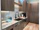 Beautiful kitchen features marble backsplash, stainless steel sink, sleek faucet, and custom wood cabinets at 166 Hammock Preserve Loop, Winter Garden, FL 34787