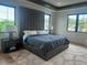 Serene main bedroom with tray ceilings, large windows, a padded headboard and sleek modern furnishings at 166 Hammock Preserve Loop, Winter Garden, FL 34787