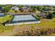 Aerial view of community tennis courts with mature trees and a nearby playground at 17437 Promenade Dr, Clermont, FL 34711