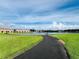 Scenic view of community lake with walking path, fountain and seating, surrounded by lush landscaping and clear blue sky at 2952 Ashland S Ln, Kissimmee, FL 34741