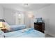 Bright bedroom featuring two twin beds, a dark wood dresser, and a stylish light fixture at 3197 Pequod Pl, Kissimmee, FL 34746