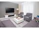 Bright living room featuring grey couches, tufted chairs, large TV, and a modern coffee table at 432 Ocean Course Ave, Davenport, FL 33896