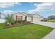 Landscaped front yard featuring a lush lawn, a palm tree, a well-maintained flower bed and a 2-car garage at 5269 Red Coral Cir, Mount Dora, FL 32757