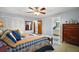 Comfortable bedroom featuring a warm quilt, ceiling fan and an adjacent bathroom for added convenience at 803 N Shore Dr, Leesburg, FL 34748