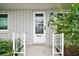 Inviting front entrance with a white door, brick accents, and lush greenery at 803 N Shore Dr, Leesburg, FL 34748