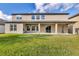 Rear exterior view of home with covered patio and large windows overlooking the yard at 10024 John Adams Way, Orlando, FL 32817