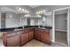 Bright bathroom featuring dual sinks with granite countertops, dark cabinetry, and a large mirror at 10024 John Adams Way, Orlando, FL 32817