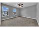 A bright bedroom with two windows, ceiling fan and neutral carpet at 10024 John Adams Way, Orlando, FL 32817