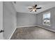 This is a bedroom with neutral colored walls, carpeted floors, a ceiling fan, and a bright window at 10024 John Adams Way, Orlando, FL 32817