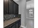 Butler's pantry with granite countertops, backsplash, and dark cabinets at 10024 John Adams Way, Orlando, FL 32817