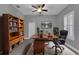 Home office with a ceiling fan, plantation shutters, a bookshelf, and a large desk at 10024 John Adams Way, Orlando, FL 32817