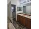 Bathroom features dual sink vanity with wood cabinets and wood-look flooring at 1004 Travertine Ter, Sanford, FL 32771