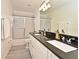 Bathroom featuring double sinks with black countertops, white cabinets and a tub with shower at 1215 Castleport Rd, Winter Garden, FL 34787