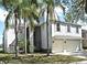 Two-story home with an attached two-car garage, pale blue paint, white trim, and lush palm trees at 1215 Castleport Rd, Winter Garden, FL 34787