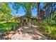 Stone patio with an outdoor fireplace, mature trees, and tropical landscaping create an outdoor oasis at 1606 The Oaks Dr, Maitland, FL 32751