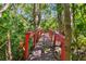 A bright red wooden bridge is set along a wooded pathway at 1606 The Oaks Dr, Maitland, FL 32751