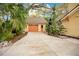 Detached garage with an orange door, surrounded by lush greenery and a spacious driveway at 1920 S Palmetto Ave, Sanford, FL 32771