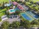 Aerial view of community featuring pool, clubhouse, tennis courts, parking, and lush greenery at 202 Stargrass Dr, Auburndale, FL 33823