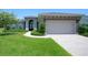 Charming single-story home with a manicured lawn, a pergola over the garage, and a double door entrance at 202 Stargrass Dr, Auburndale, FL 33823