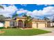 Charming one-story home featuring a three-car garage, lush lawn, and vibrant red front door, beneath a bright, cloudy sky at 2582 Greenwillow Dr, Orlando, FL 32825