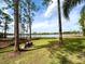 A picturesque backyard with a scenic lake view, lush green grass, and mature trees at 2674 Kingsdale Dr, Deltona, FL 32738