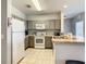 A well-lit kitchen features tiled floors, grey cabinets, and white appliances at 3175 Feltrim Pl # 304, Kissimmee, FL 34747