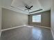 This bedroom features a tray ceiling, fan, window, and gray tile flooring at 345 Gardenia Ct, Kissimmee, FL 34759