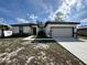 A white one story home with a two car garage, lawn, and walkway leading to the front door at 345 Gardenia Ct, Kissimmee, FL 34759