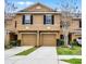 Townhouse with a beige exterior, two stories, black shutters, and two garage doors at 3658 Caruso Pl, Oviedo, FL 32765