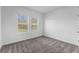 Well-lit bedroom featuring plush gray carpeting and two windows for natural light at 5376 Dagenham Dr, Davenport, FL 33837