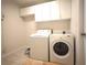 Bright laundry room features a washer, dryer, storage cabinets and tiled floor at 6065 Dory Way, Tavares, FL 32778