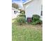 View of the side yard showcasing the lush landscaping, air conditioner and a glimpse of the neighborhood at 6065 Dory Way, Tavares, FL 32778