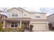 Two-story home with tan siding, stone accents, a covered porch, and an attached two-car garage at 643 Taft Dr, Davenport, FL 33837