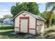 A utility shed with a brown trim and a decorative eagle adornment sits on a grassy lot at 759 Swallow St, Deltona, FL 32725