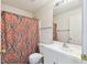 A cozy bathroom with a patterned shower curtain and a vanity with a sink and mirror at 939 Van Loon Ct, Kissimmee, FL 34758