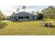 Spacious backyard with a screened patio and seating area with lush green grass, and mature landscaping at 1045 S State Road 415, New Smyrna Beach, FL 32168