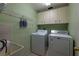 A functional laundry room featuring a washing machine, dryer, utility sink, and storage cabinets at 1045 S State Road 415, New Smyrna Beach, FL 32168