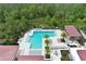 Aerial view of a community pool with lounge chairs and palm trees with a large forest nearby at 14384 Alafaya Oak Bnd, Orlando, FL 32828