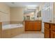 Bathroom featuring a soaking tub with tile surround, and wood cabinets at 1562 Travertine Ter, Sanford, FL 32771