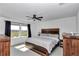 Bright main bedroom featuring a modern ceiling fan, a large window, and stylish rustic wood furniture at 1795 Nw 44Th Ct Rd, Ocala, FL 34482
