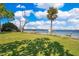 Waterfront property with expansive green lawn and private dock under a beautiful sky at 2613 Nela Ave, Belle Isle, FL 32809